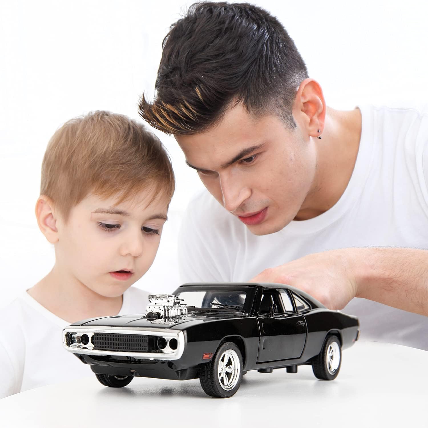 Man and child examining a black model car on a white background