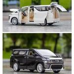 Two toy models of vans, one white and one black, on a road with blurred greenery in the background.